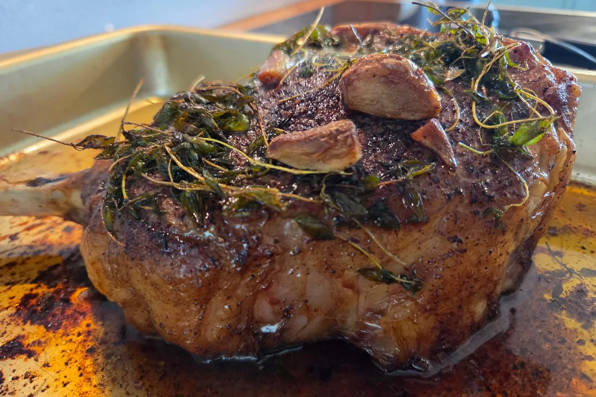 Grillet tomahawk-steik med urter, skåret opp i en stekepanne