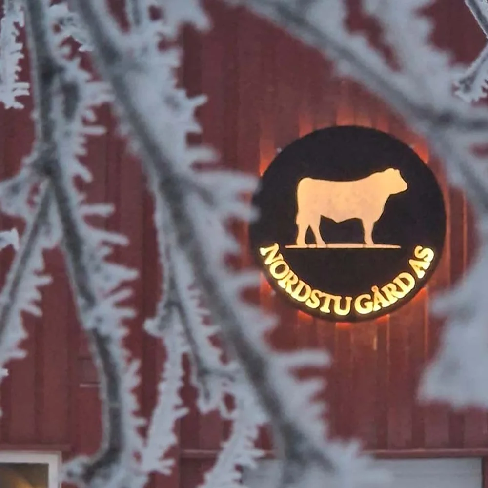 Nordstu Gård AS-merket med Angus-oksen, brent inn i den røde uthusveggen, dekket av rim