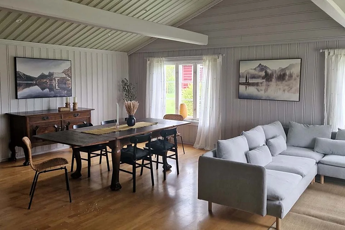 Stue i Østerdalstua med spisebord, sofagruppe og vindu mot tunet